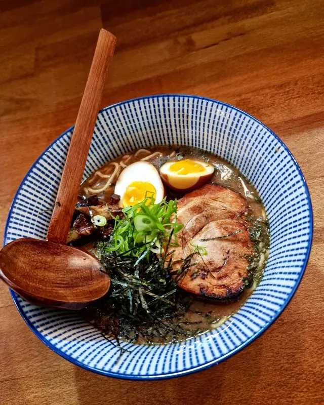 A bowl of ramen with sliced pork, egg and nori